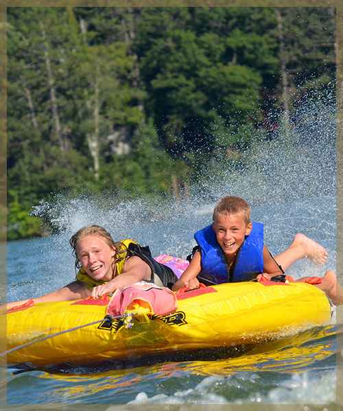 Two kids hanging on to tube as they move through water