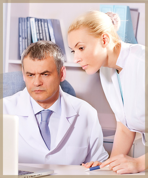 Doctor and nurse reading lab results on laptop