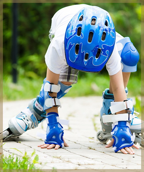 Young kid falling on roller blades with knee pads, helmet, and wrist guards