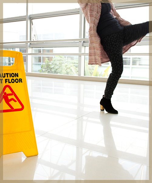 Person slipping on floor next to Caution Wet Floor sign
