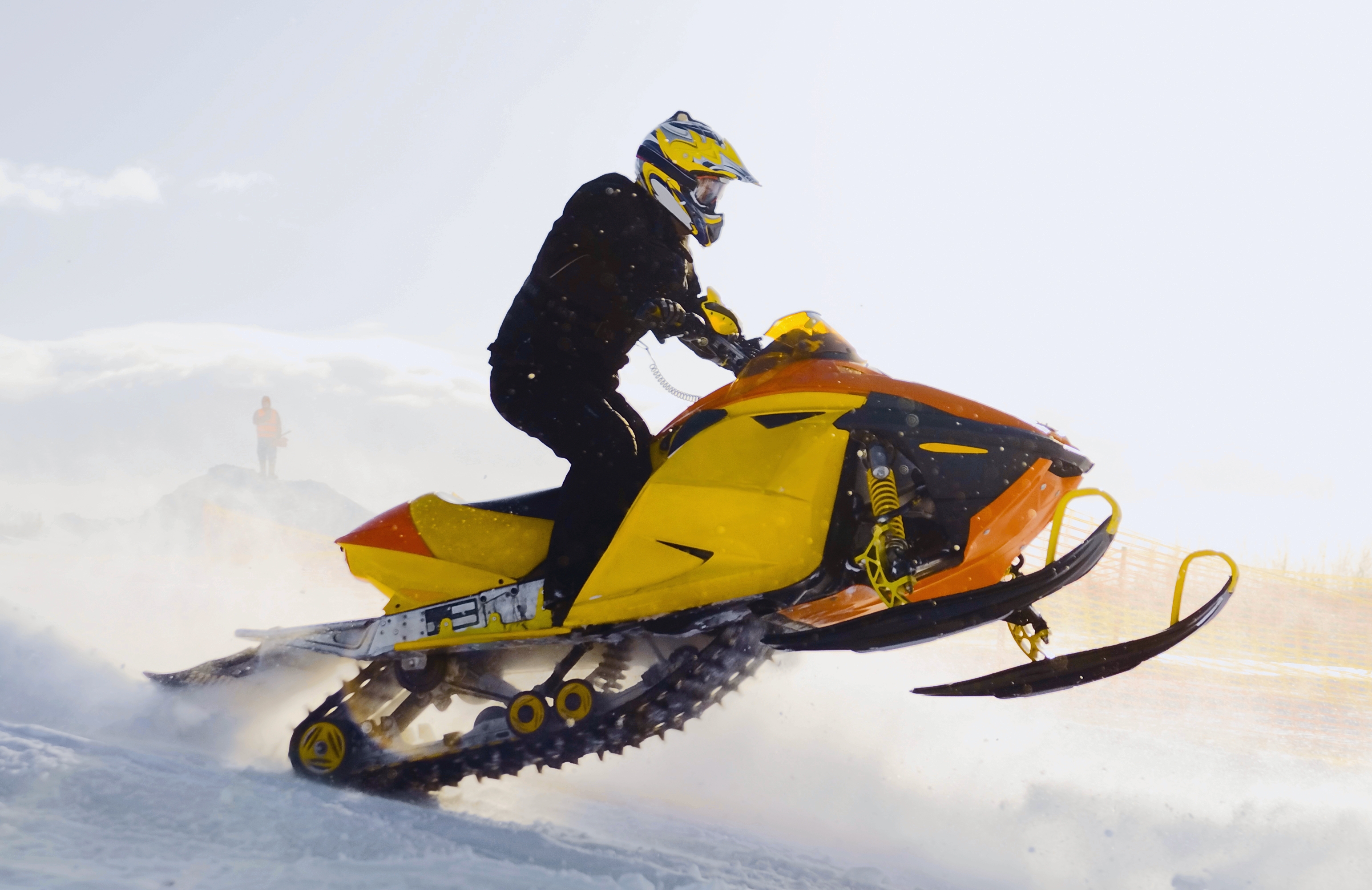 man driving yellow snowmobile on snow