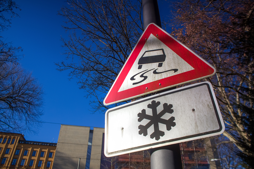 Slippery road sign and snowflake sign on pole