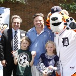 Scott Goodwin smiling with Detroit Tigers mascot, two young girls, and their dad