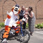 Detroit Tigers mascot on bike while others smile for their photo at Law Day