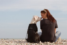 Woman and dog looking at each other and sitting on rocks