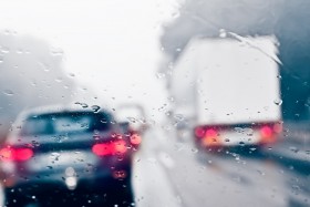 Rainy windshield behind vehicles on highway