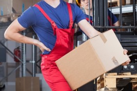 Warehouse worker carrying a box and holding back in pain