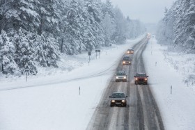 Cars driving on a snowy road through a winter blizzard