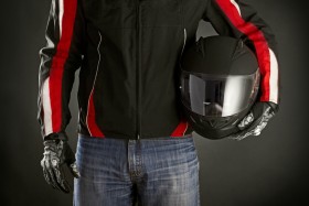 Motorcyclist holding helmet while wearing biker jacket and gloves