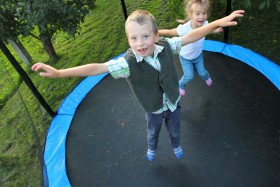 Two kids jumping on enclosed trampoline