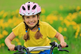 Girl smiling while riding bike with helmet on