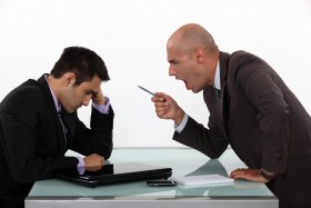 Businessman yelling at another businessman while angrily pointing pen at him