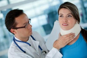 Doctor fitting neck brace to woman's neck