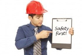 Construction worker with hardhat pointing to Safety First sign