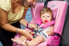 Mom buckling in child into pink carseat