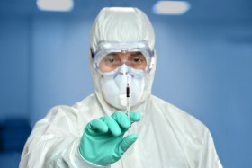 Nurse in hazmat suit holding a syringe