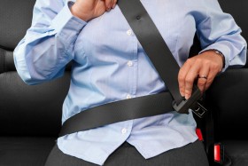 Woman putting on seat belt in car