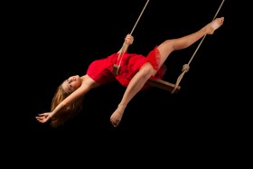 Female circus performer swinging on wooden swing