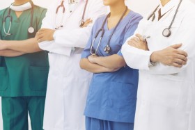 Doctors and nurses lined in a row with their arms crossed