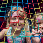 Girls smiling through mesh lining of inflatable bounce house