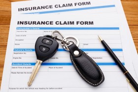 Keys and pen on top of insurance claim form