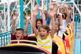 Kids and adults on roller coaster with hands up