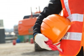 Construction worker holding hard hat at construction site