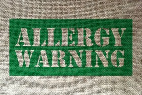 Allergy Warning written in green on burlap material