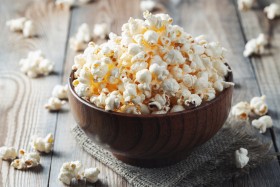 Wooden bowl filled with popcorn on table