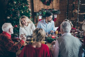 Family talking and laughing around dinner table at Christmas