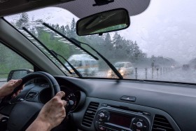Person driving through rain with windshield wipers on