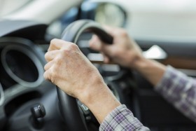 Person holding steering wheel while driving