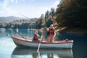 Grandfather and grandson fishing off of wooden boat