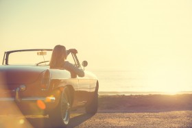 Woman sitting in convertible watching the sunset