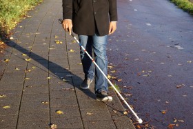 Blind person walking with cane.