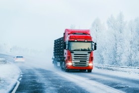 Truck and a car driving on a snowy road.
