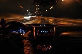 View of the road from the front seat of a car being driven at night.