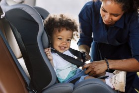 Mother buckling child into car seat