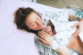 A mother holds her newborn baby in a hospital bed.