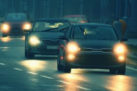 Cars driving at dusk with headlights on.