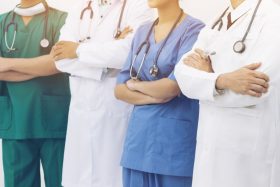 A group of healthcare workers stand with folded arms.
