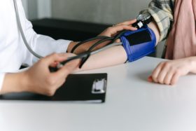 A doctor uses a device to check a patient's blood pressure on their arm.