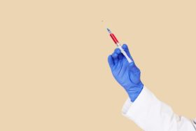A syringe is held by a hand with a blue glove.