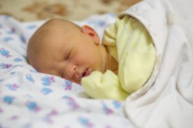 A newborn baby wrapped in a yellow blanket.