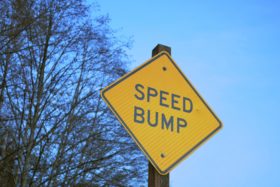 A yellow road sign warning drivers about speed bumps.
