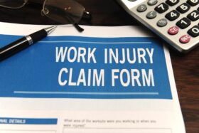 Workplace injury claim form on a table next to a calculator.