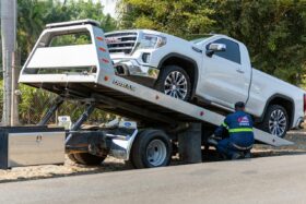 White truck loaded onto a tow truck.